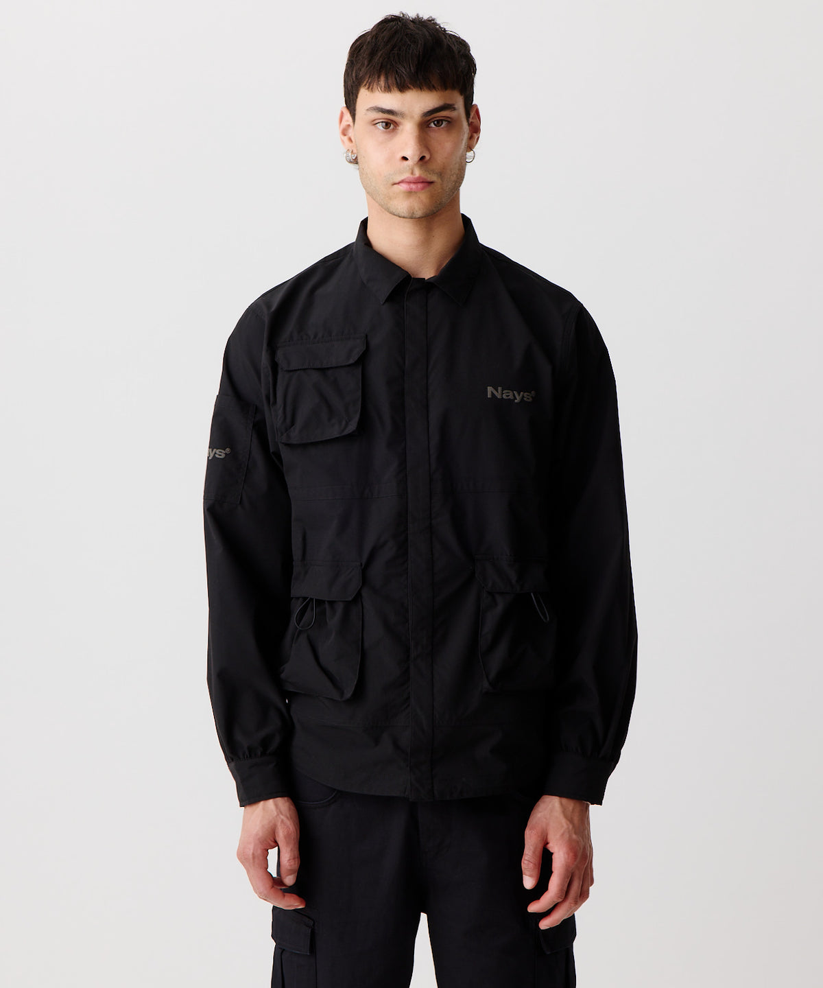 Nays Utility Shirt, eine leichte Shirt-Jacke mit Reverskragen, aufgesetzten Taschen, wasserabweisendem Finish und elastischen Drawstrings getragen von einem Mann in der frontalen Ansicht.