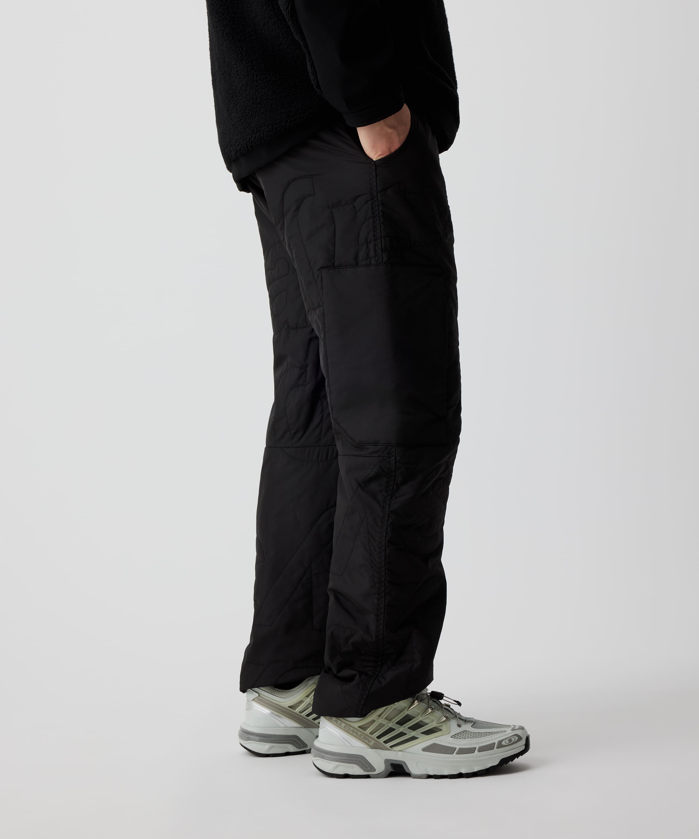 Person trägt Nays Thermo Hose mit elastischem Bund und mehreren Taschen, ideal für kalte Temperaturen und Outdoor-Aktivitäten. Sichtbar sind die Steppoptik und weiße Sneakers.