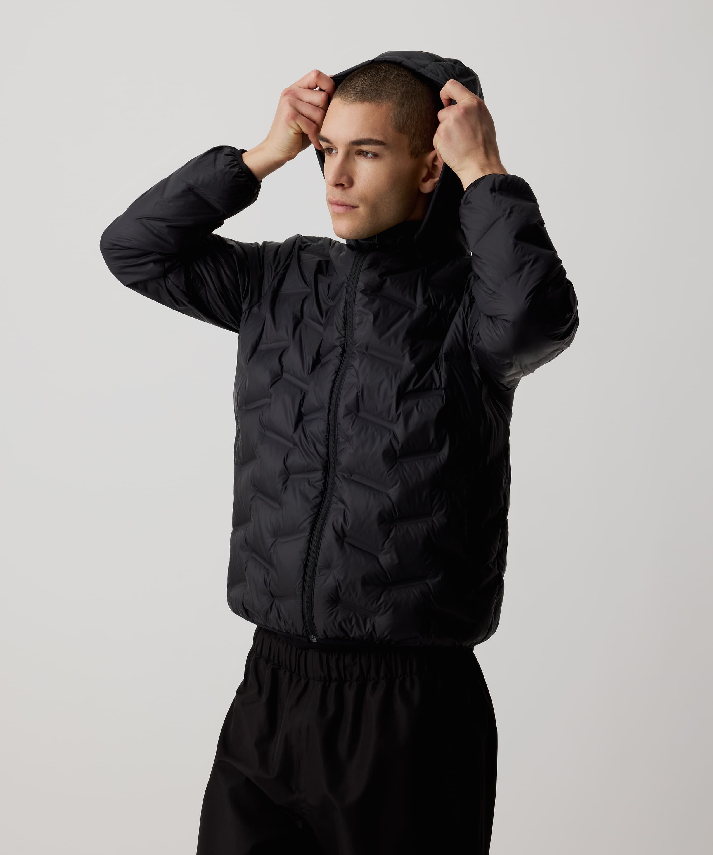 Ein Mann trägt die Nays Lightweight Down Jacket mit Kapuze, Reißverschlüssen und Seitentaschen, ideal für kalte Tage und Outdoor-Abenteuer.