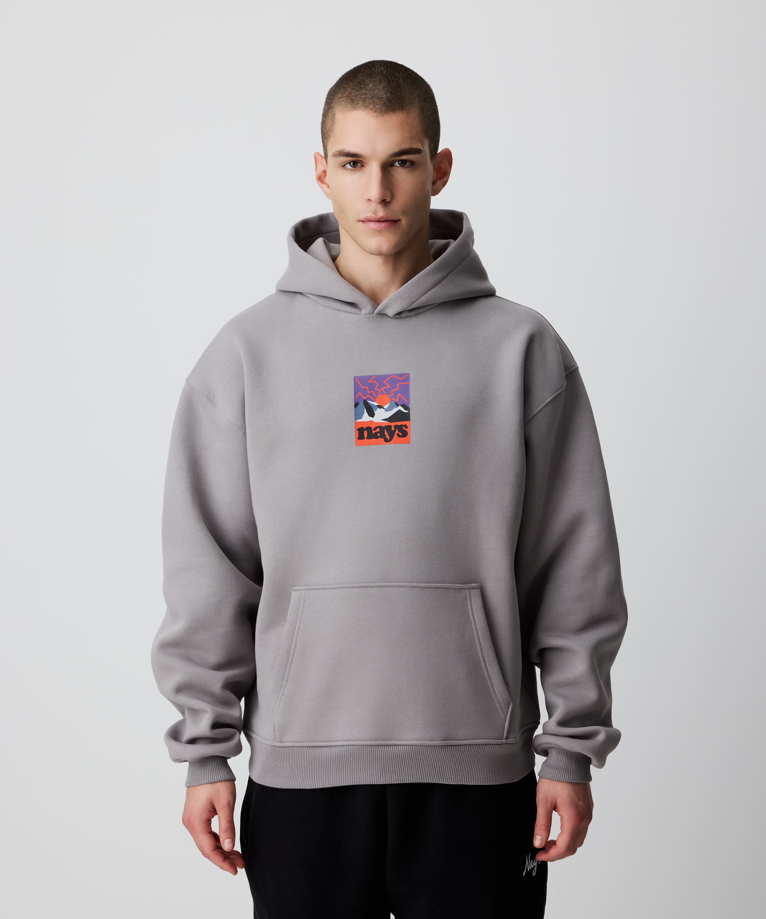 Mann trägt Nays Retro Sun Hoodie, graues Kapuzensweatshirt mit auffälligem Grafik-Print, lässiger Schnitt, ideal zum Layern, komfortabel gebürstete Innenseite.