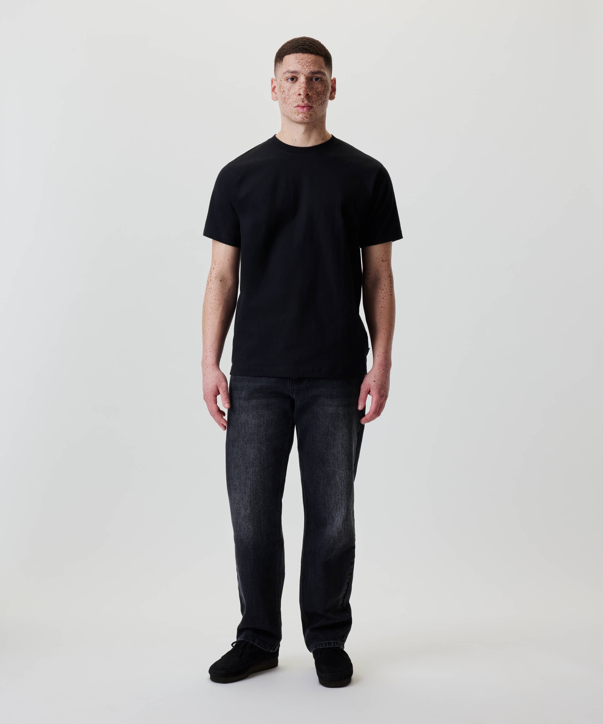 Ein junger Mann trägt Nays Regular Fit Jeans mit geradem Bein und 5-Pocket-Design, ideal für den Alltag, kombiniert mit einem schwarzen T-Shirt.