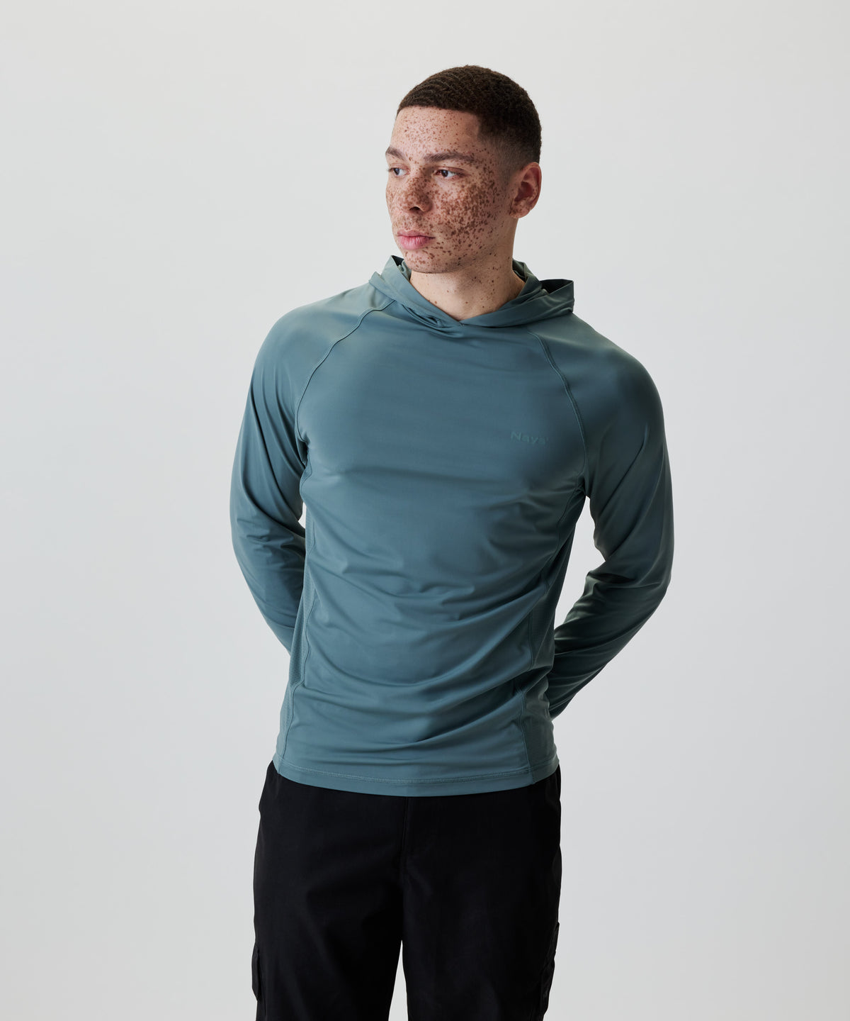 Ein junger Mann trägt das Nays UV 50+ Hooded Longsleeve mit Raglanärmeln und Kapuze, ideal für Sonnenschutz bei Aktivitäten.