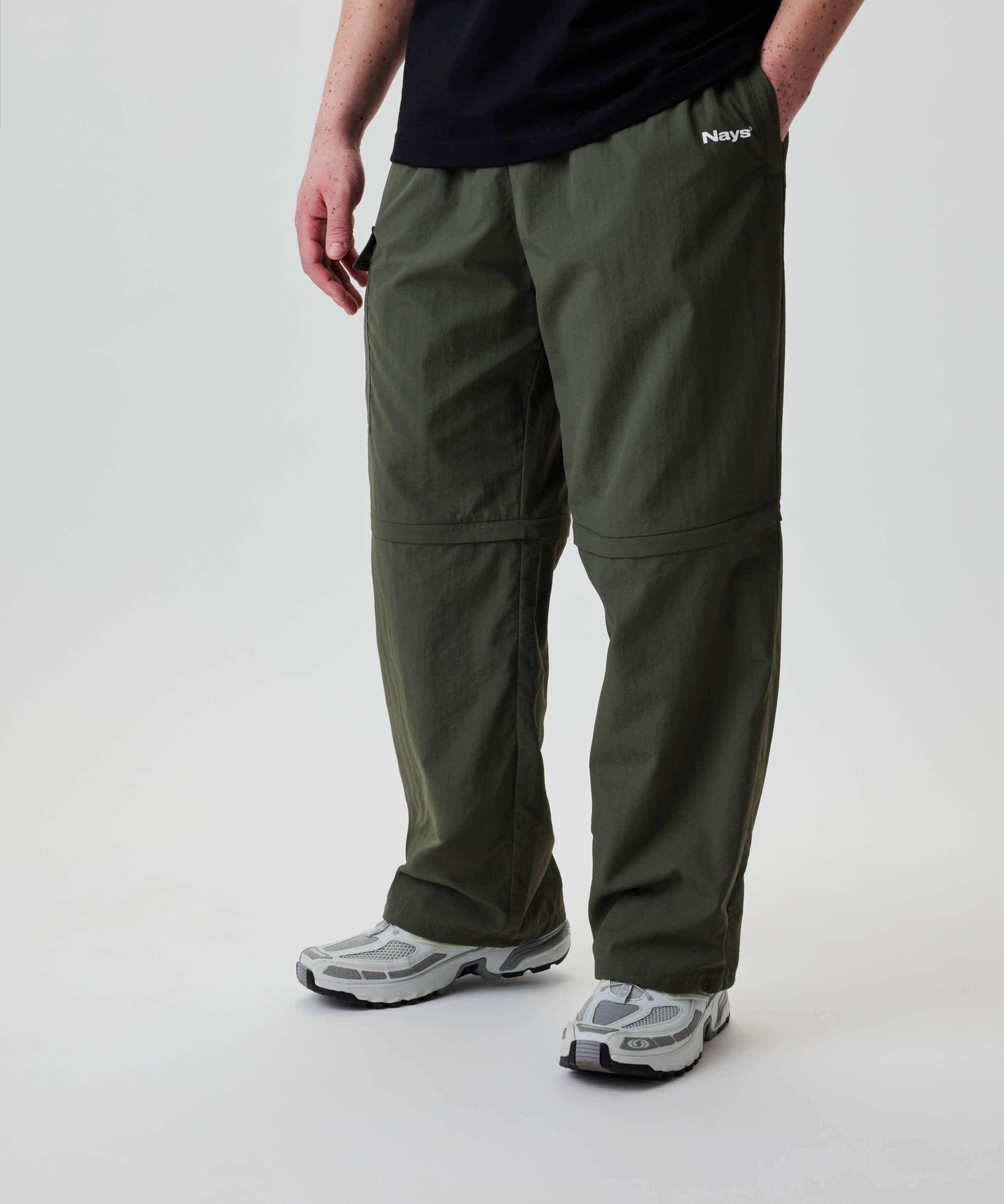 Nays Lightweight Zip Off Pants mit abnehmbaren Beinen und praktischen Reißverschlusstaschen, getragen mit Trailrunning-Sneakern, ideal für flexible Outdoor-Aktivitäten.