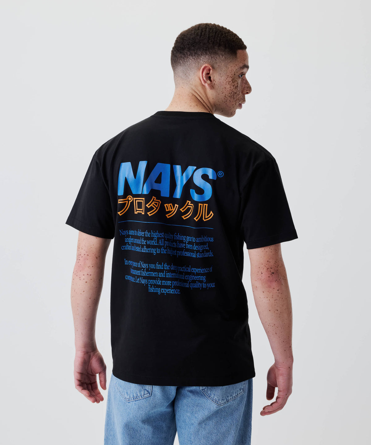 Junger Mann trägt das Nays Pro Tackle International Tee mit großem Rückenprint „NAYS“ und katakanischem Text, ideal für Freizeit und Alltag.