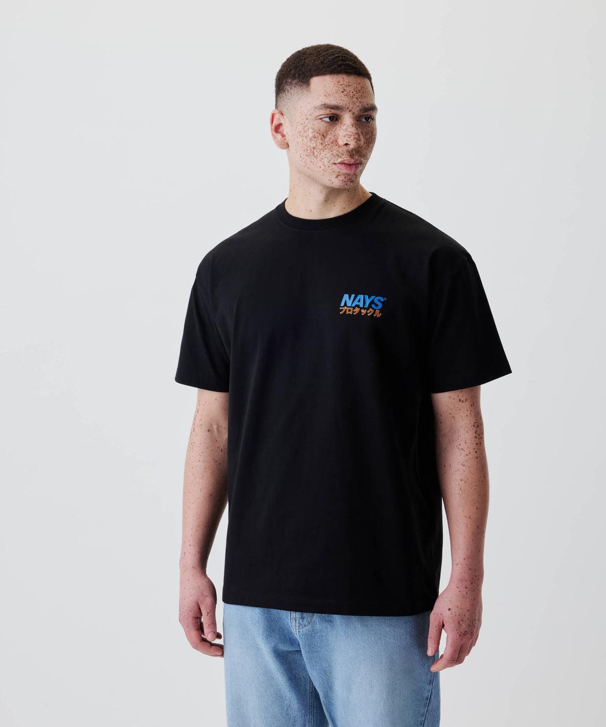 Ein junger Mann trägt das Nays Pro Tackle International Tee mit kleinem Brustprint, perfekt für Alltag und Freizeit, aus 100% Baumwolle.