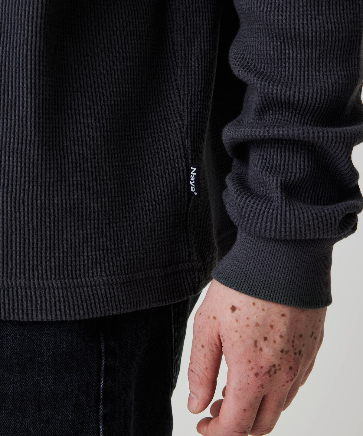 Person trägt das Nays Classic Waffle Longsleeve in Anthrazit, das durch sein strukturiertes Material und dezentes Nays®-Label an der Seitennaht besticht.