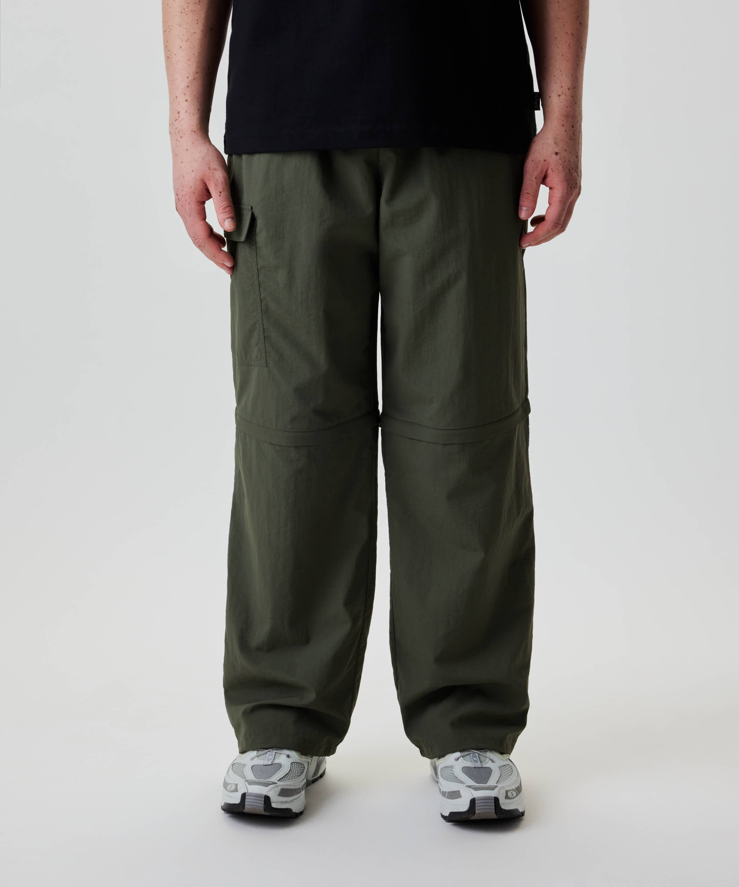 Unterkörper einer Person in Nays Lightweight Zip Off Pants, wandelbar in Shorts durch Reißverschlüsse an den Knien, ideal für vielseitige Outdoor-Aktivitäten.