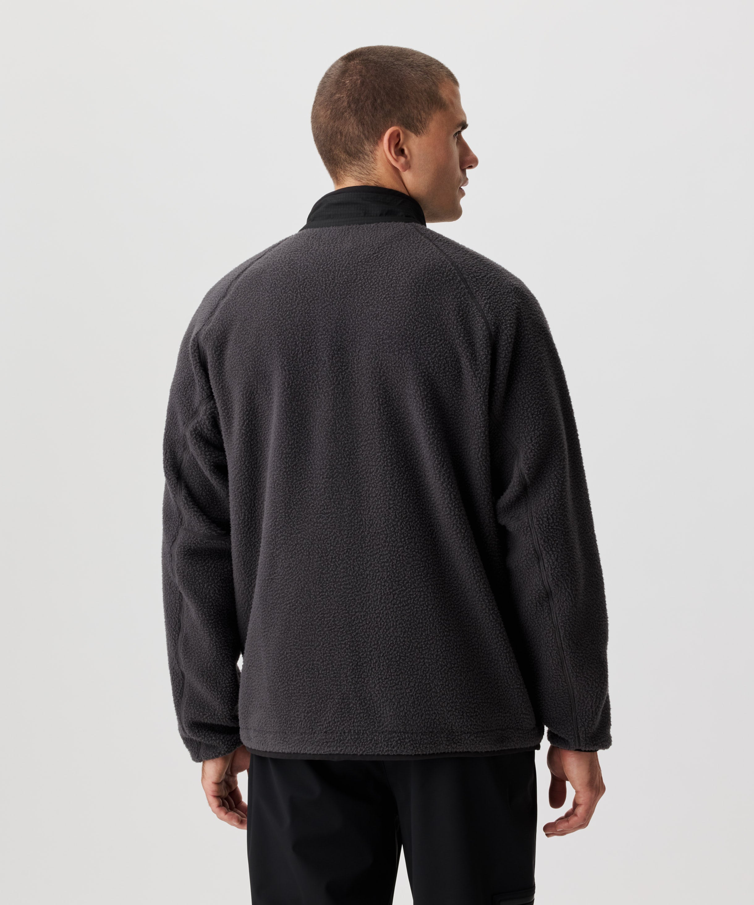 Rückansicht Mann in dunkel-grauer Fleece-Jacke.