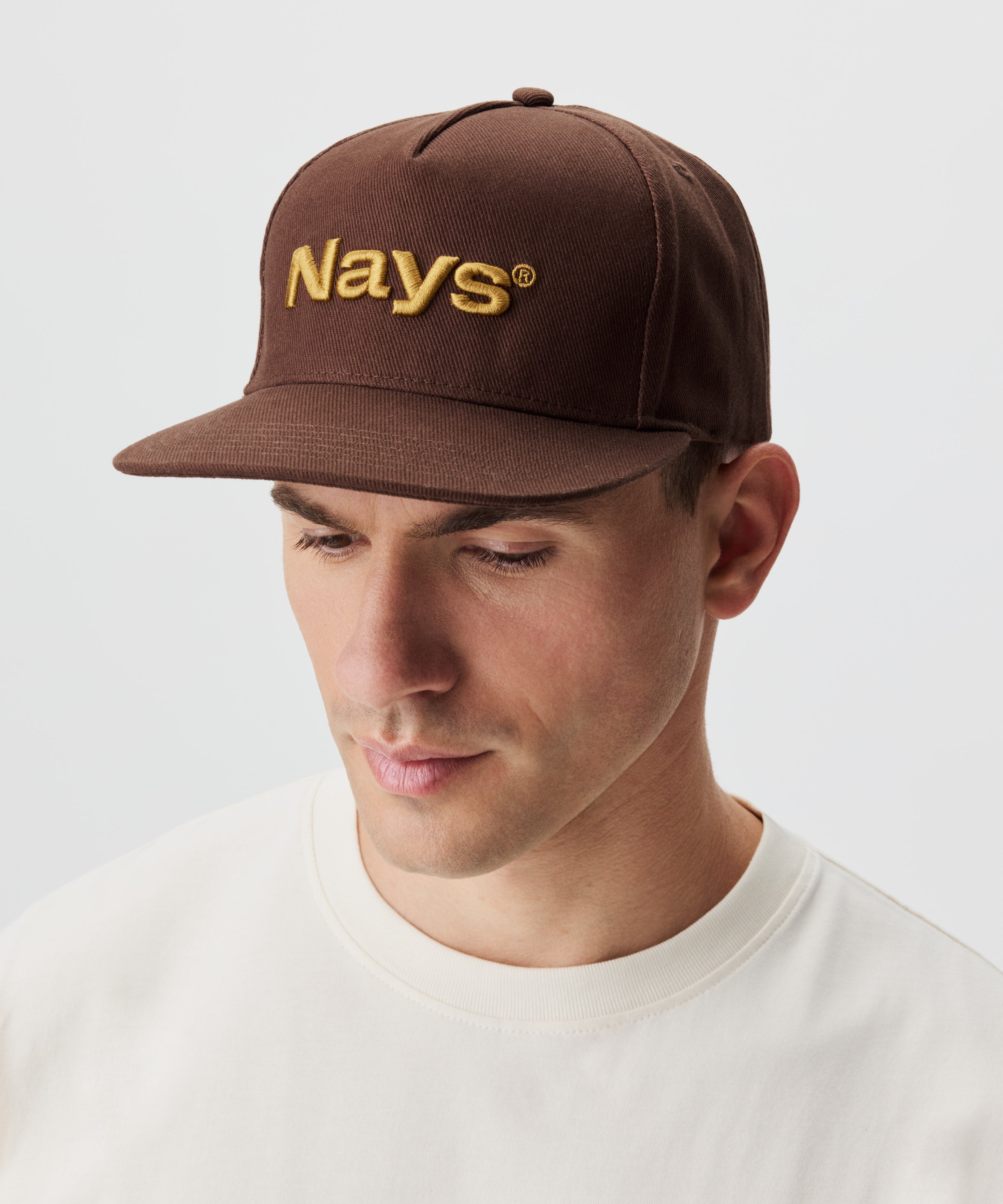 Seitenansicht Mann mit brauner Cap. Ein gold-gelbes Nays-Logo ziert die Cap.