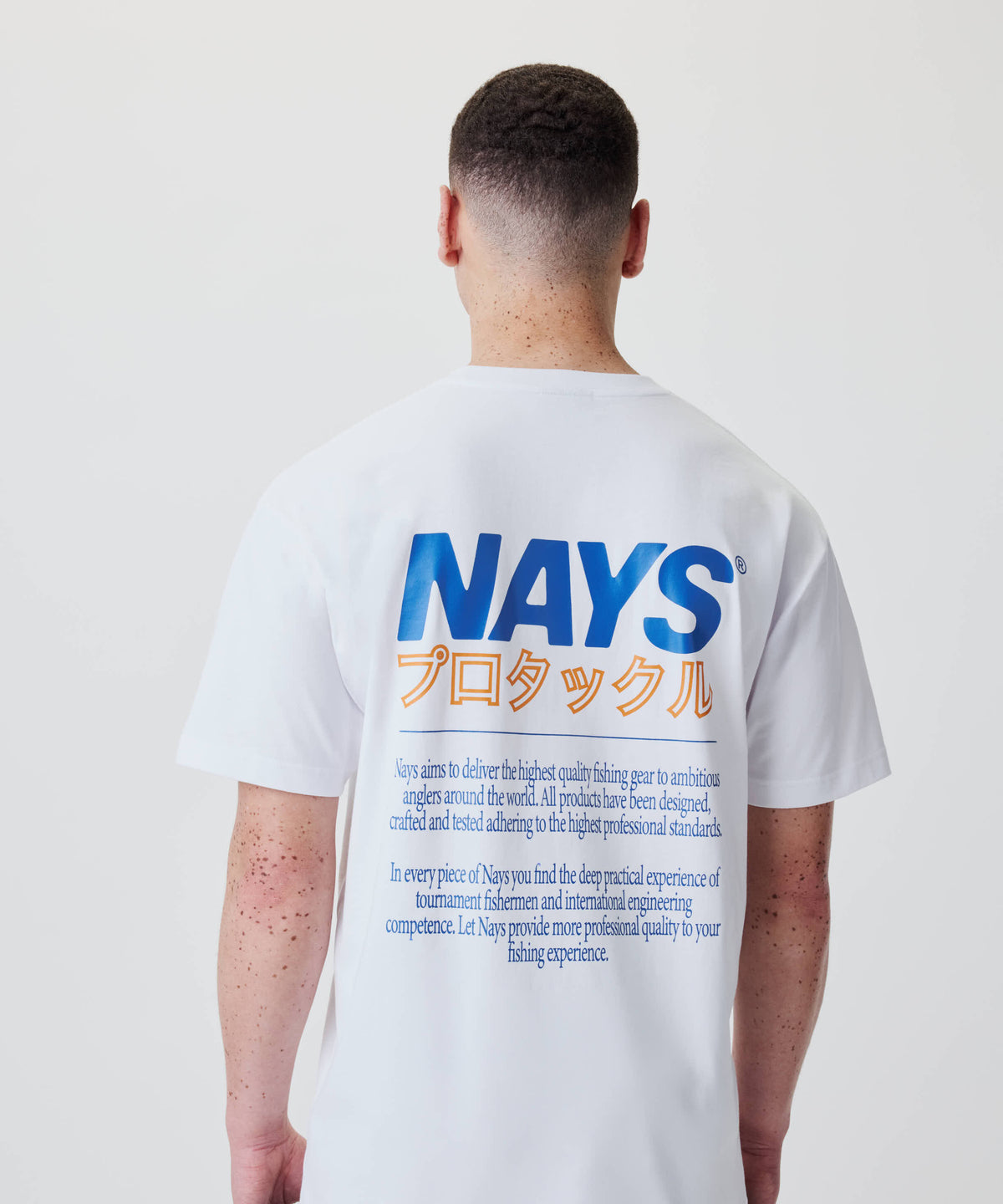 Rückansicht einer Person im Nays Pro Tackle International Tee mit großem Rückenprint: „NAYS“ in Blau, japanische Katakana und englischer Text darunter.