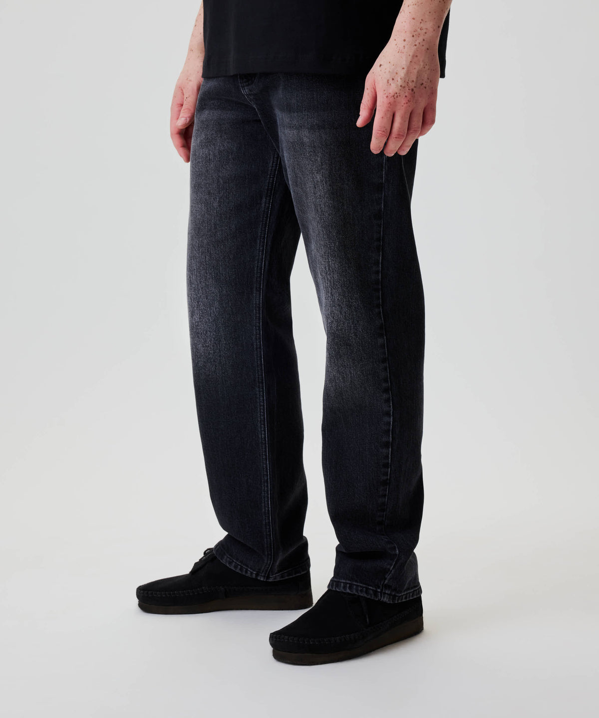 Nays Regular Fit Jeans in dunkel gewaschenem Denim, gerade geschnitten. Getragen mit schwarzen Mokassins. Sichtbare Hände zeigen den klassischen 5-Pocket-Stil.
