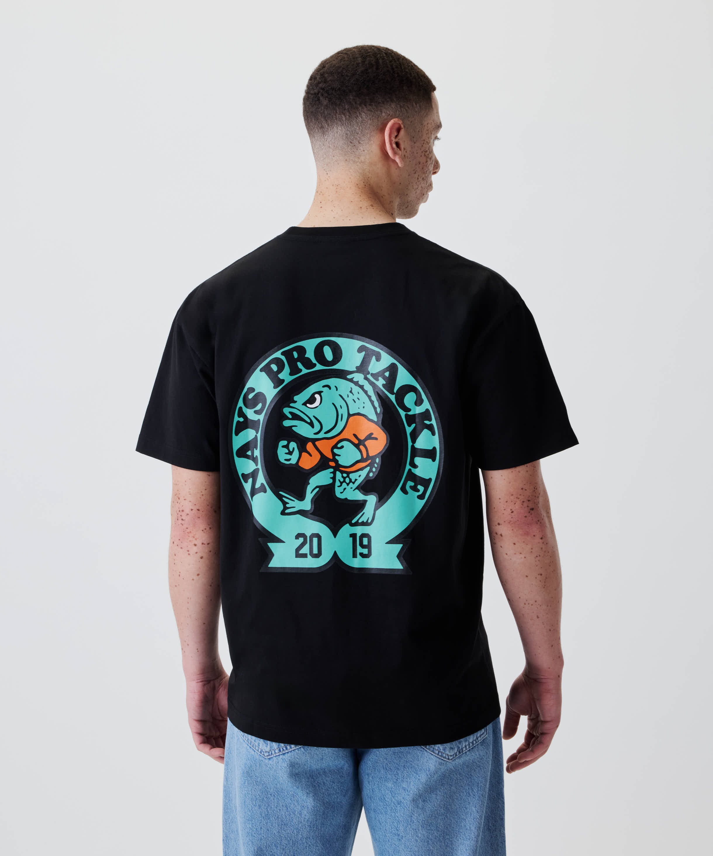 Rückansicht des Nays College Print Tee mit großem JAYS PRO TACKLE Logo und Cartoon-Fisch auf dem Rücken. 100% Baumwolle, lässiger Alltagsstil.