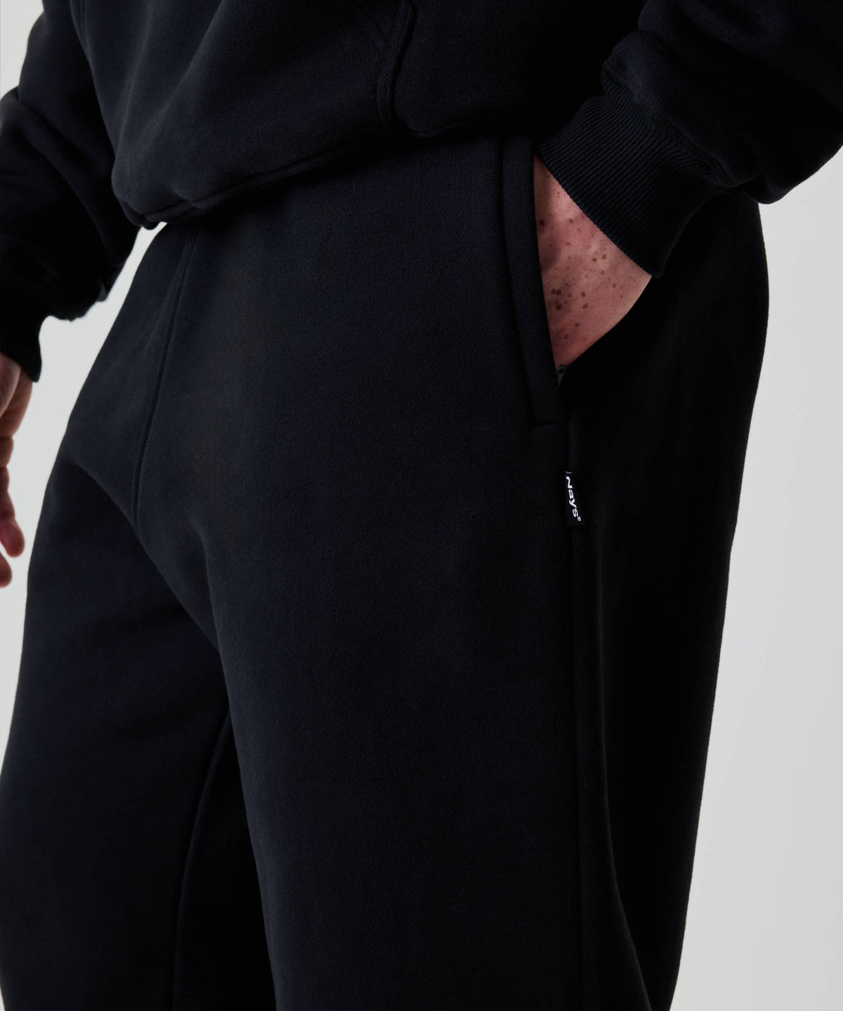 Nahaufnahme der Nays Baggy Sweatpants, zeigt eine Hand in der Seitentasche. Die Jogginghose bietet Komfort und einen lässigen Look.