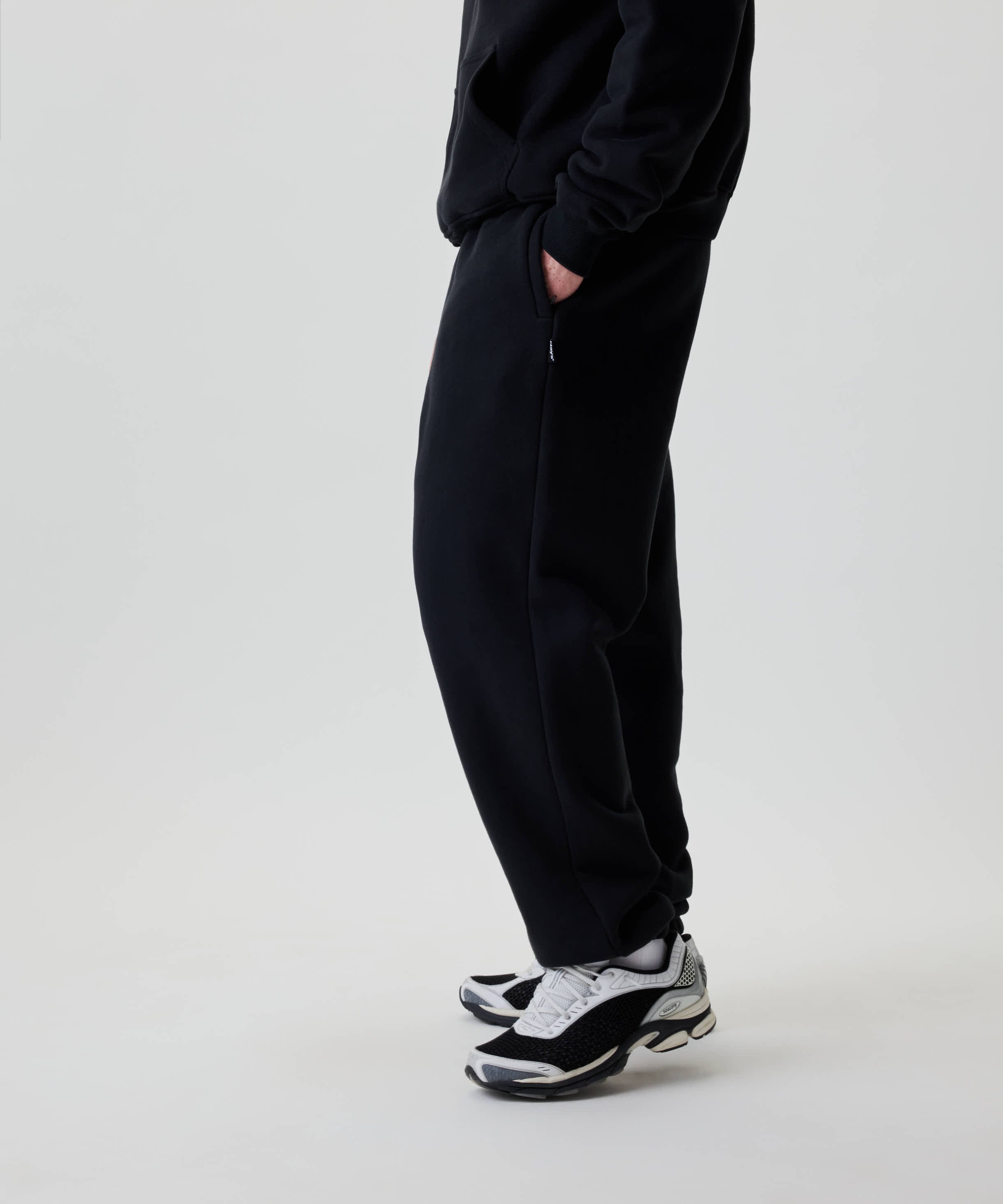 Nays Baggy Sweatpants in Schwarz, locker sitzend mit praktischen YKK Zipper-Taschen. Trägt eine dezente Stickerei auf der Rückseite für eleganten Alltagskomfort.