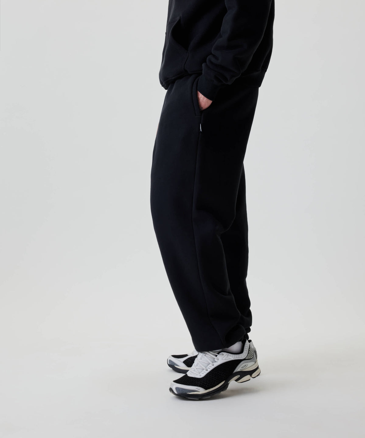 Nays Baggy Sweatpants in Schwarz, locker sitzend mit praktischen YKK Zipper-Taschen. Trägt eine dezente Stickerei auf der Rückseite für eleganten Alltagskomfort.